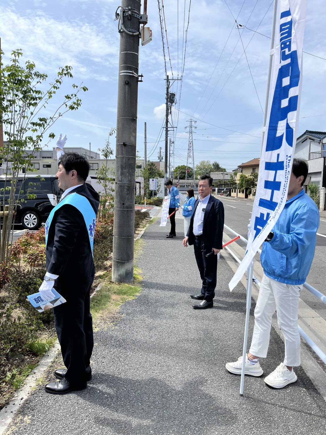 のぼり旗を持って道路沿いで活動